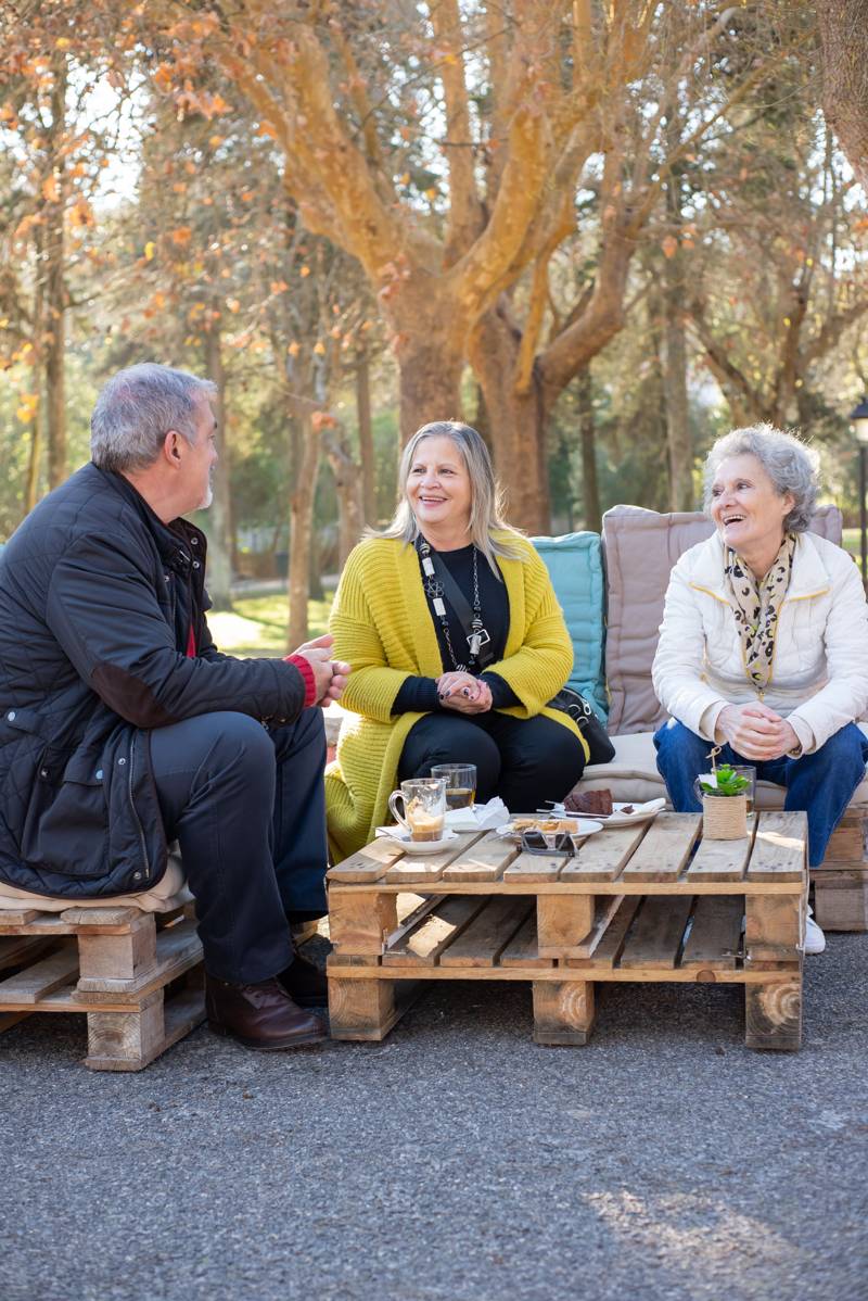 Three older people chatting and laughing together around a table