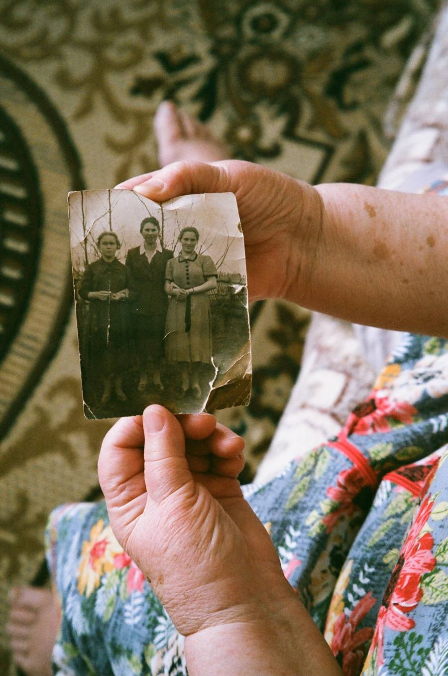 Elderly hands holding a worn black and white family photograph